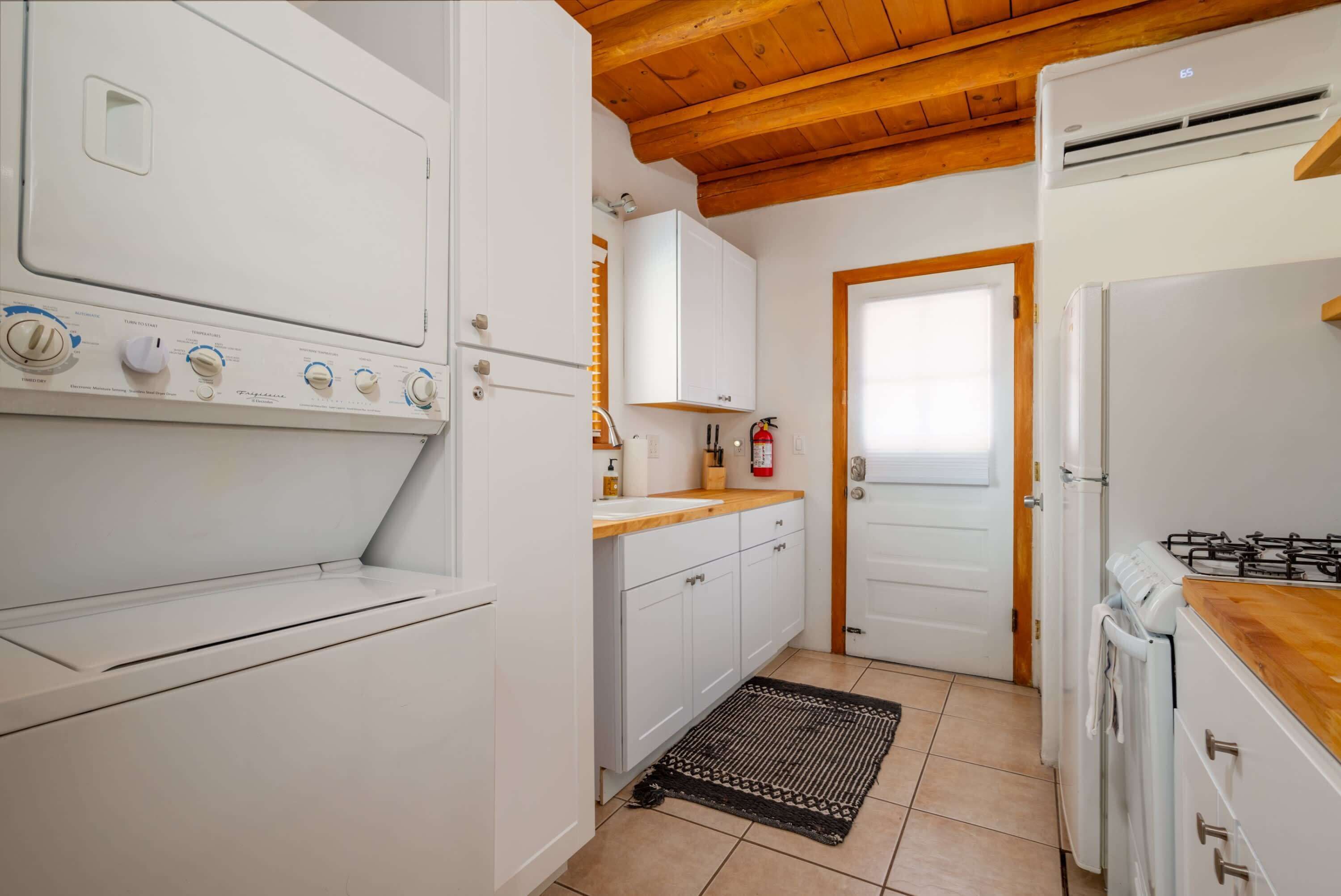 A compact kitchen with a built-in oven, a gas stove, white cabinets, and a wooden ceiling.
