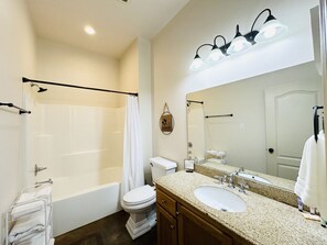 Une salle de bain avec une baignoire, des toilettes, un lavabo et un grand miroir.