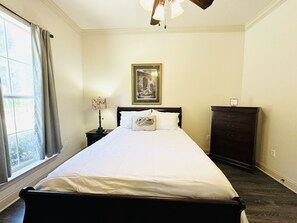 A neatly made bed in a room with a window, a framed picture on the wall, and a dresser. - Villa 3, spacious townhouse in Tickfaw, LA (Tickfaw)