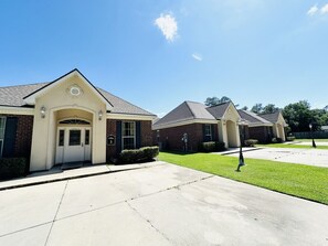 A residential building with a brick facade, a white entrance, and a well-maintained lawn.