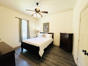 A bedroom with a bed, a ceiling fan, a dresser, and a window with curtains. - Villa 3, spacious townhouse in Tickfaw, LA (Tickfaw)