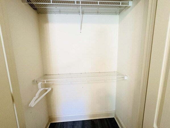 A small, enclosed closet with a metal shelf and a white hanger.