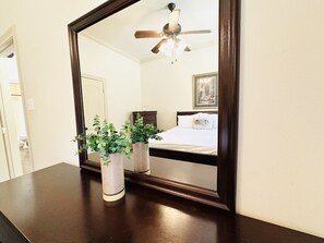 A bedroom with a large mirror, a ceiling fan, and two potted plants on a dresser. - Villa 3, spacious townhouse in Tickfaw, LA (Tickfaw)