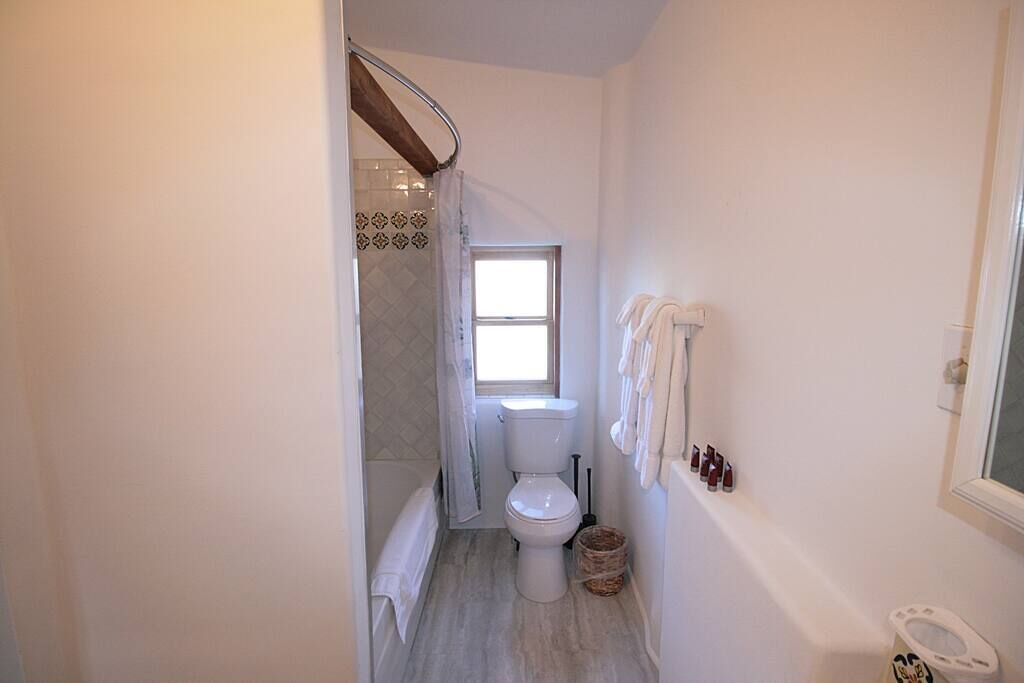 Un baño con inodoro, ventana, ducha y toallero.