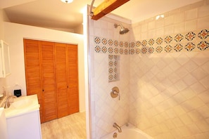 A bathroom with a shower, a sink, and a wooden door.