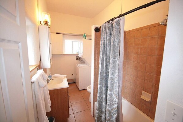 A bathroom with a white sink, a toilet, and a shower with a patterned curtain.