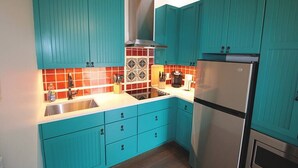Una cocina con armarios azul verdoso, un refrigerador de acero inoxidable y un salpicadero de azulejos.