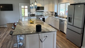 A modern kitchen with a marble countertop, stainless steel appliances, and pendant lighting.