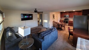 A living room with a sofa, a coffee table, and a TV mounted on the wall. There is a dining area with a table and chairs, and a kitchen with cabinets and appliances. - Great location, 10 min downtown Denver. 15 to Red Rocks. Regis university 5 min  (Mountain View)