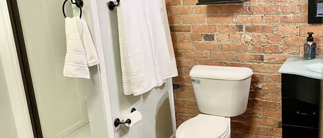 A bathroom with a glass shower enclosure, white toilet, and a black cabinet.