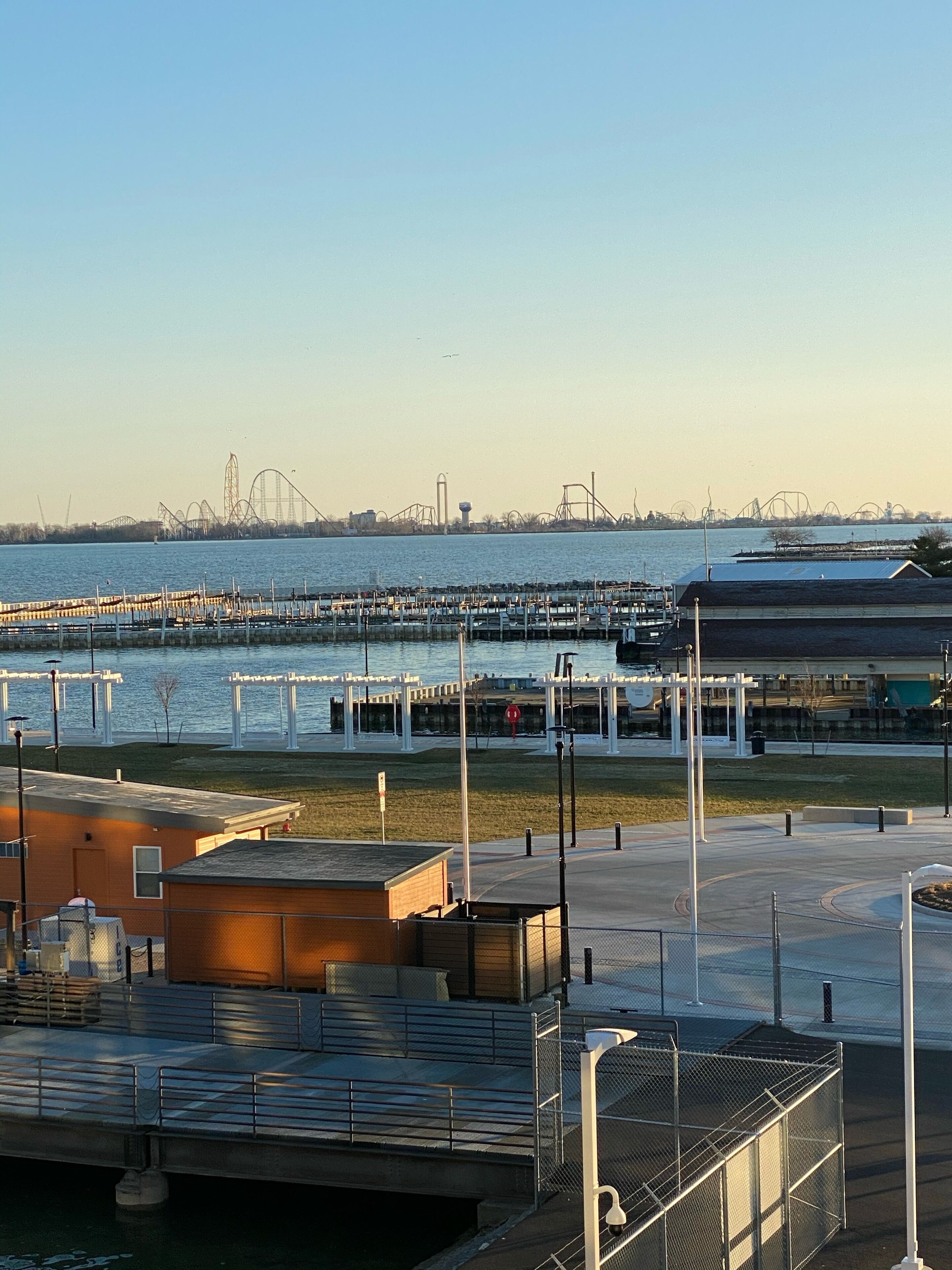 Vista al front marítim amb una muntanya russa al fons, un port esportiu amb vaixells i un edifici amb teulada plana.