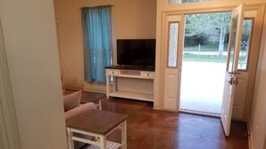 Een kleine kamer met een televisie, een tafel en een bank.