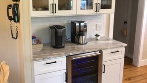 Une cuisine moderne avec des meubles blancs, un four encastré et une machine à café posée sur le plan de travail.
