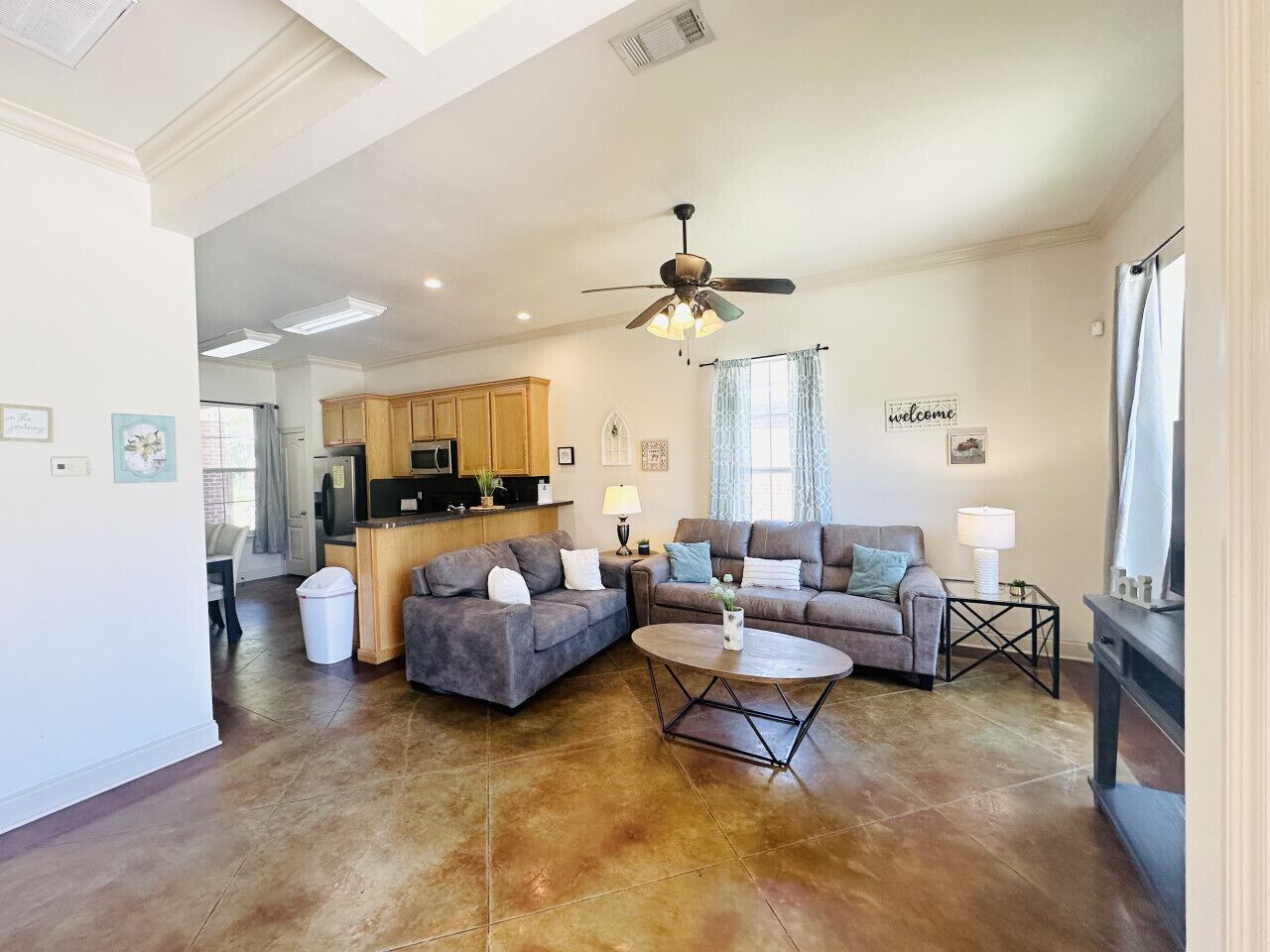 A spacious living room with a large gray sectional sofa, a round coffee table, and a ceiling fan.