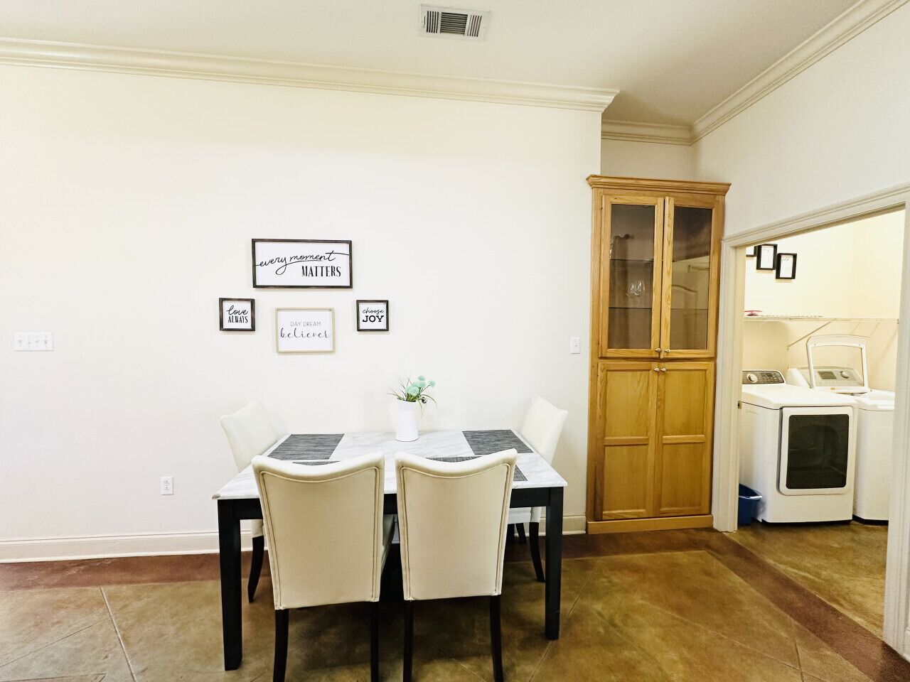 A dining area with a table and chairs, a cabinet, and a laundry area with washing machines.