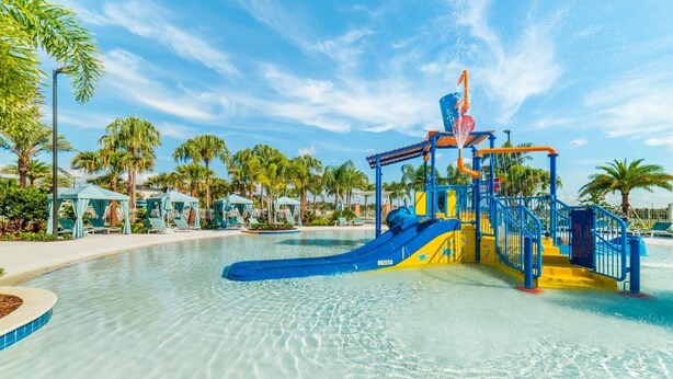 Een waterpark met een blauw en geel speelconstructie, helder zwembadwater en palmbomen.