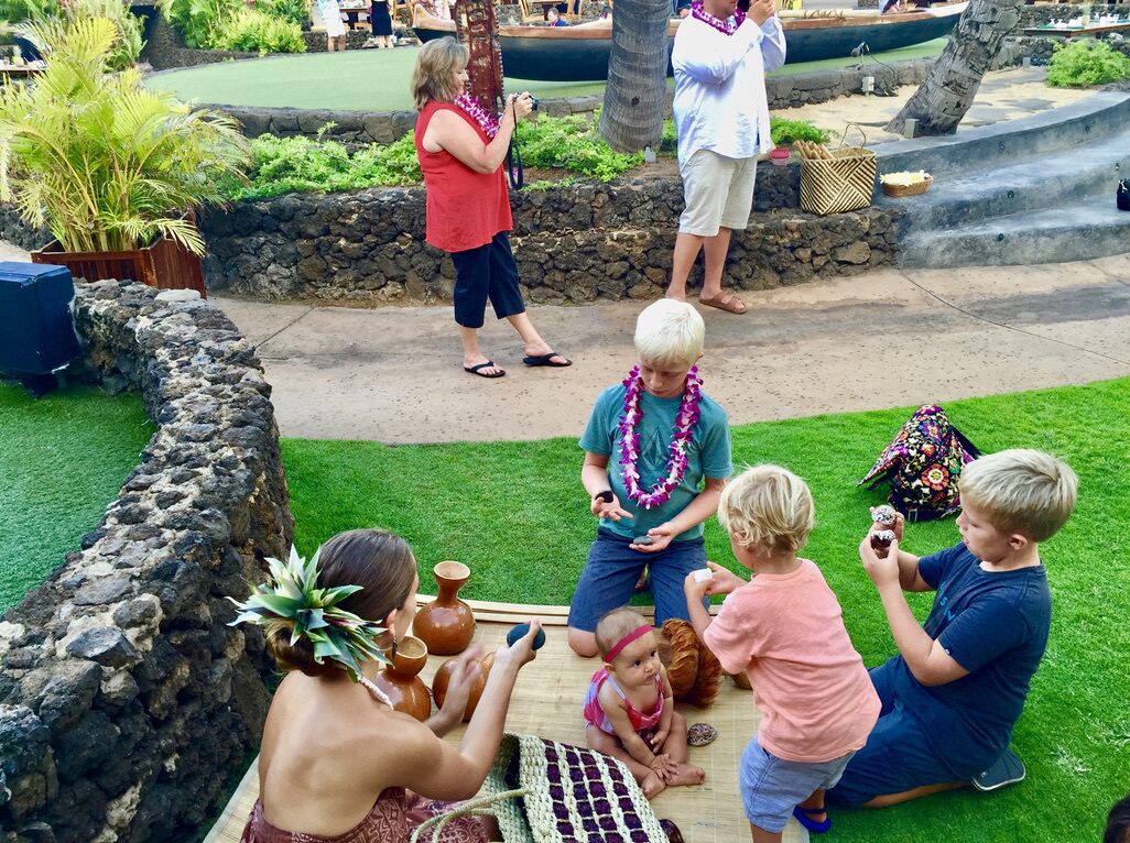 A group of people sitting on the grass, some holding pottery.