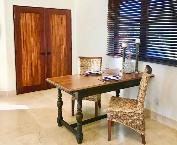 A dining table with a woven chair, a wine glass, and a candle holder. - Indulge, just steps to pristine beaches, restaurants & shopping. (Kihei)