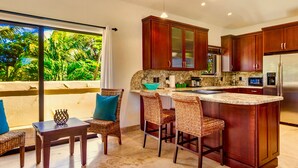 A modern kitchen with a large island, bar stools, and a dining table with chairs.