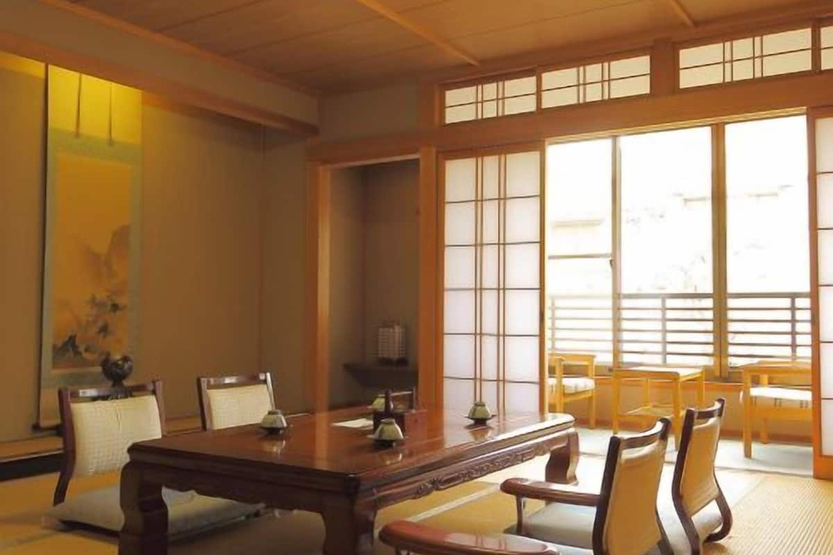 Perinteinen japanilaistyylinen huone, jossa on tatamimatto, matala puupöytä ja shoji-liukuovet.