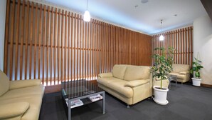 Een moderne woonkamer met een beige bank, een glazen salontafel en twee potplanten.