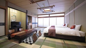 Een hotelkamer met een bed, een televisie, een eettafel en tatami matten.