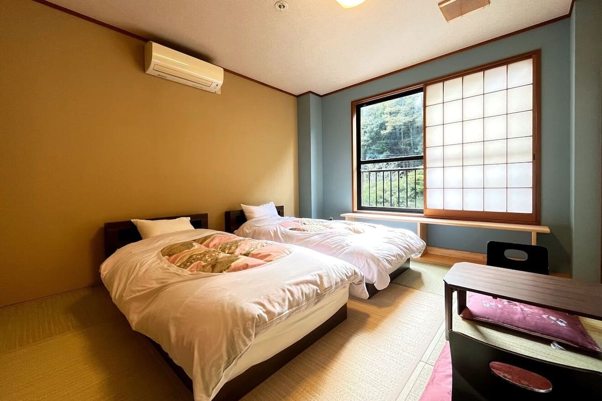 Une chambre d’hôtel avec deux lits, une fenêtre donnant sur un beau paysage, un bureau et une chaise.