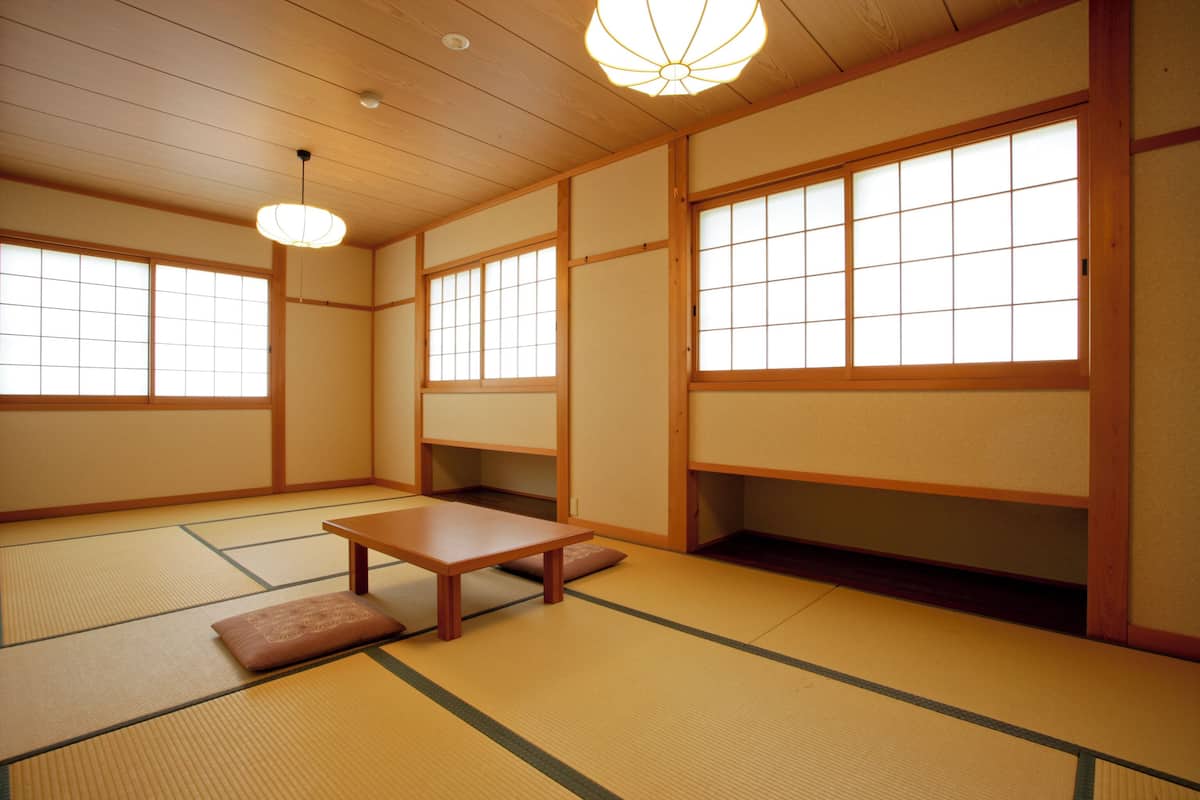 Une pièce de style japonais traditionnel, avec un sol recouvert de tatamis, des portes coulissantes et une petite table en bois.