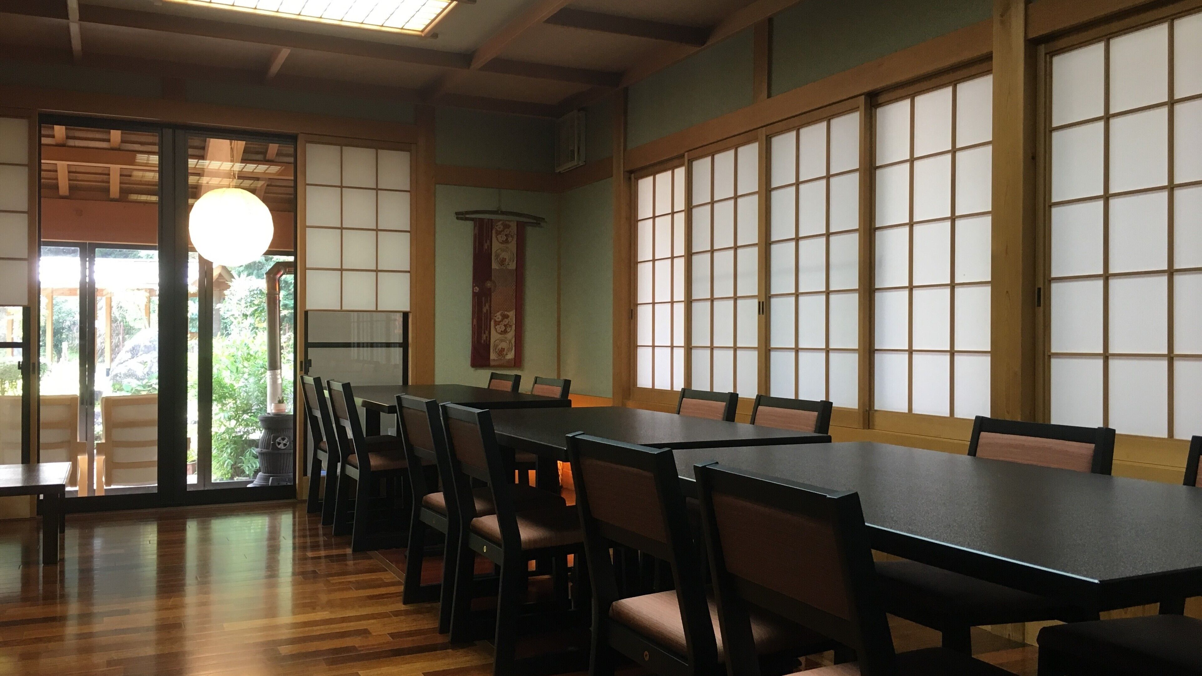 A traditional Japanese room with tatami mats, sliding doors, and a low wooden table with chairs.