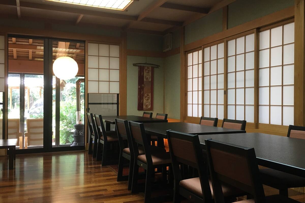 Une pièce de style japonais traditionnel, avec des tatamis, des portes coulissantes et une basse table en bois entourée de chaises.
