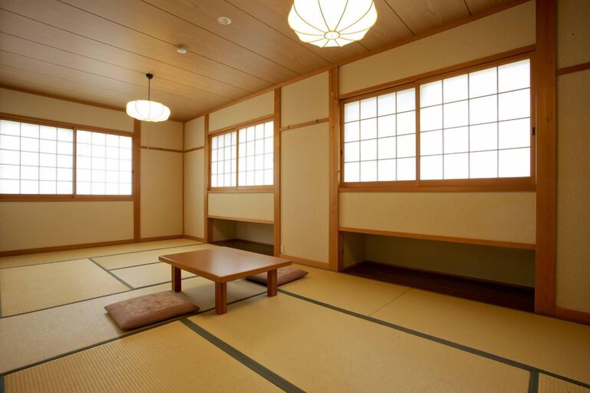 Une pièce de style japonais traditionnel, avec un sol recouvert de tatamis, des portes coulissantes et une petite table en bois.