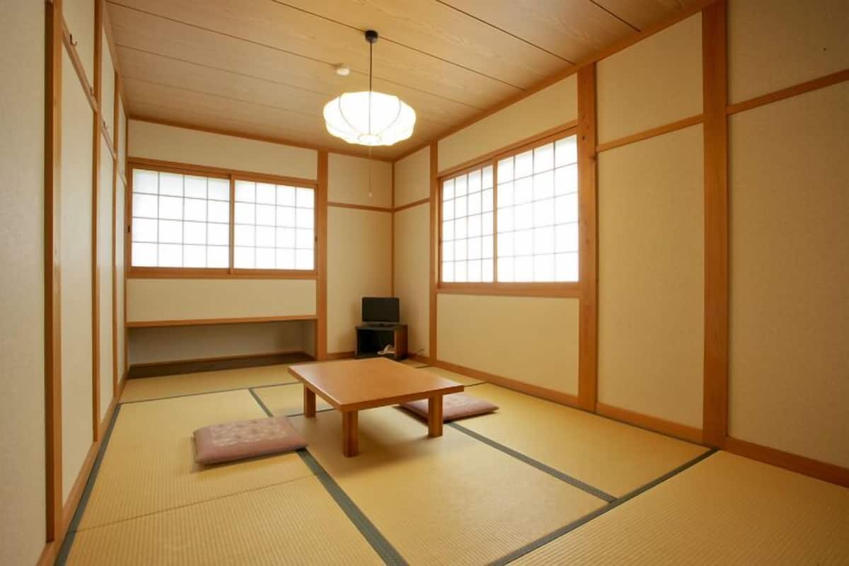 Une pièce de style japonais traditionnel, avec un sol recouvert de tatamis, une table basse et des portes coulissantes.