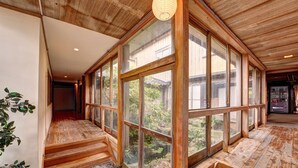 A spacious room with large windows, wooden flooring, and a staircase leading to an upper level. - Sakataya Ryokan (Yuza)