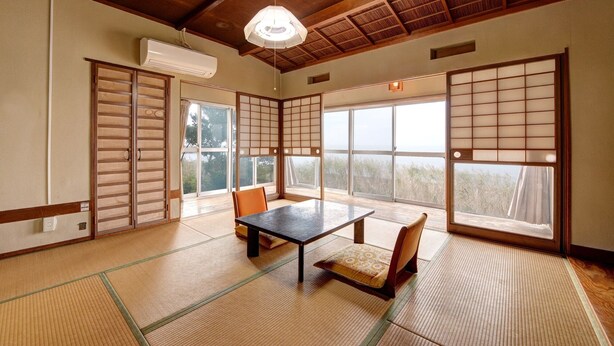 A traditional Japanese room with tatami flooring, sliding doors, a table, and chairs. - Sakataya Ryokan (Yuza)