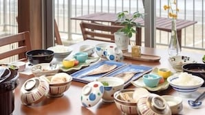 A dining table with various dishes and utensils, a potted plant, and a view of the sea. - Ocean Front Hamada-kan (Hitachinaka)