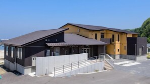 A modern building with a flat roof, large windows, and a concrete staircase leading to the entrance. - Ocean Front Hamada-kan (Hitachinaka)