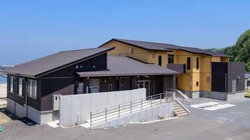 A modern building with a flat roof, large windows, and a concrete staircase leading to the entrance.