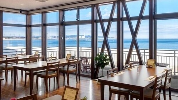 A spacious dining area with large windows offering a view of the sea and city skyline. - Ocean Front Hamada-kan (Hitachinaka)