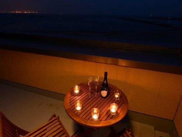 A round wooden table with candles and a bottle, set against a coastal backdrop. - Ocean Front Hamada-kan (Hitachinaka)