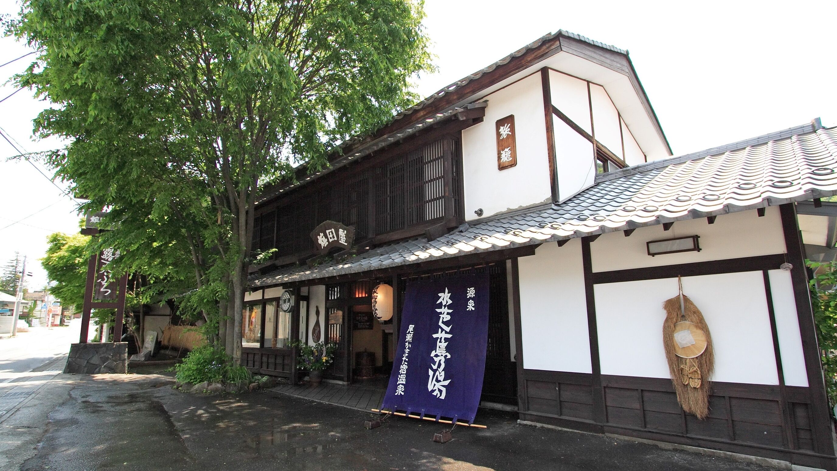 A traditional Japanese building with a signboard, wooden exterior, and a tiled roof.