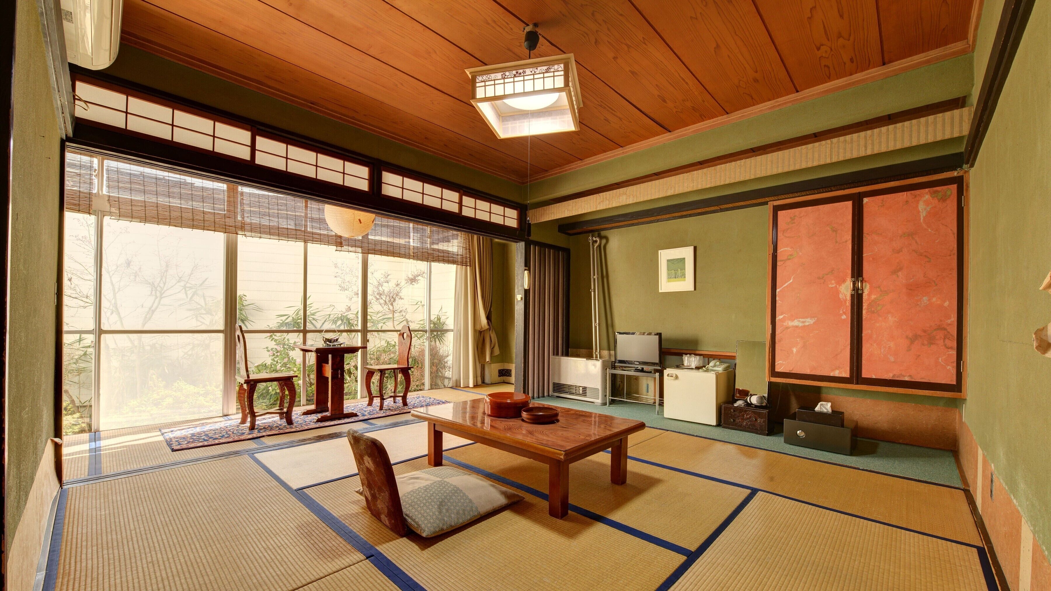 A traditional Japanese room with tatami flooring, a wooden table, a TV, and a sliding door.