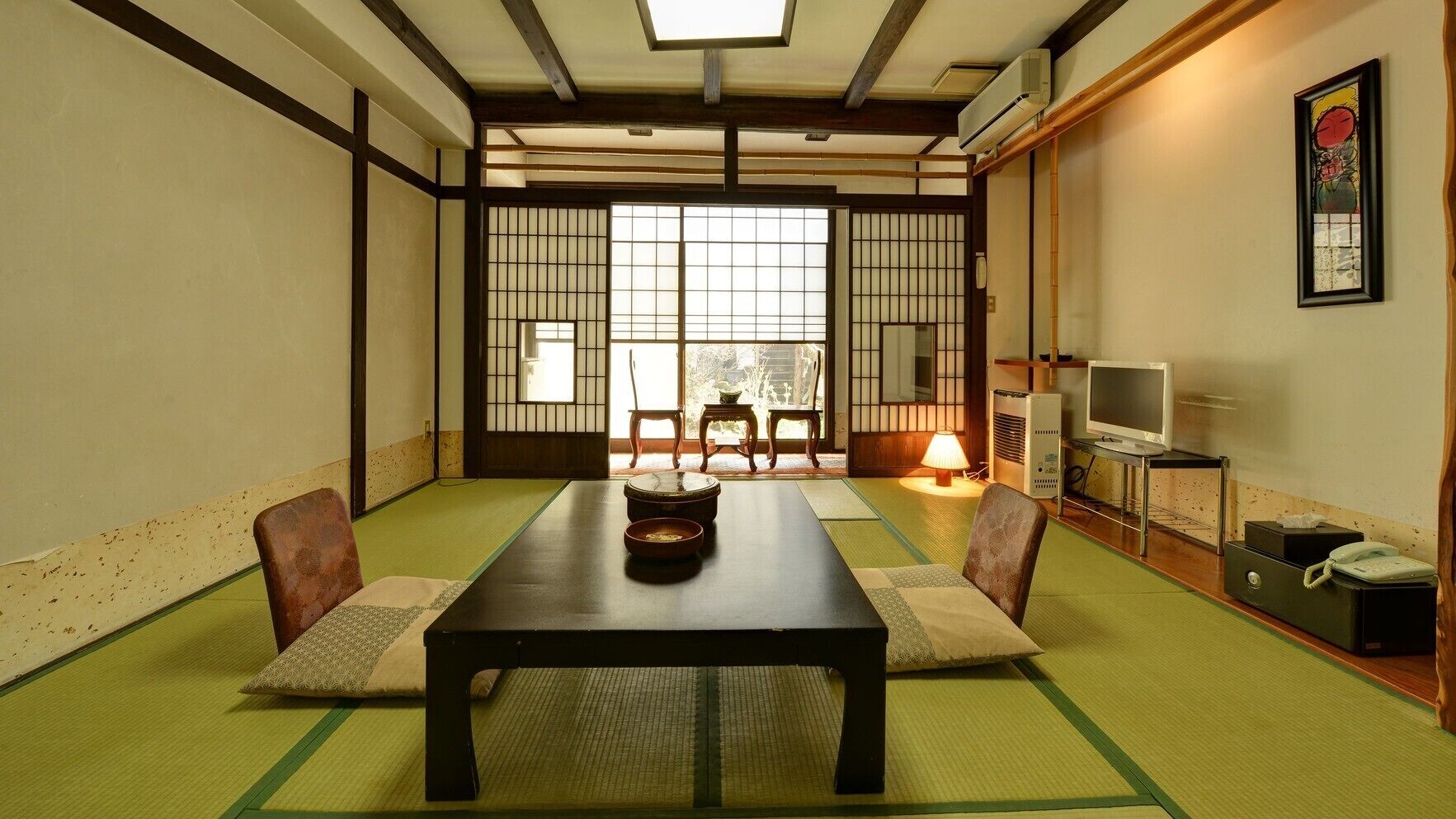 A traditional Japanese room with tatami flooring, a low table, and sliding doors.