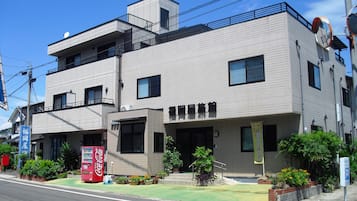 A two-story building with a flat roof, multiple windows, and a Coca-Cola vending machine on the ground floor.