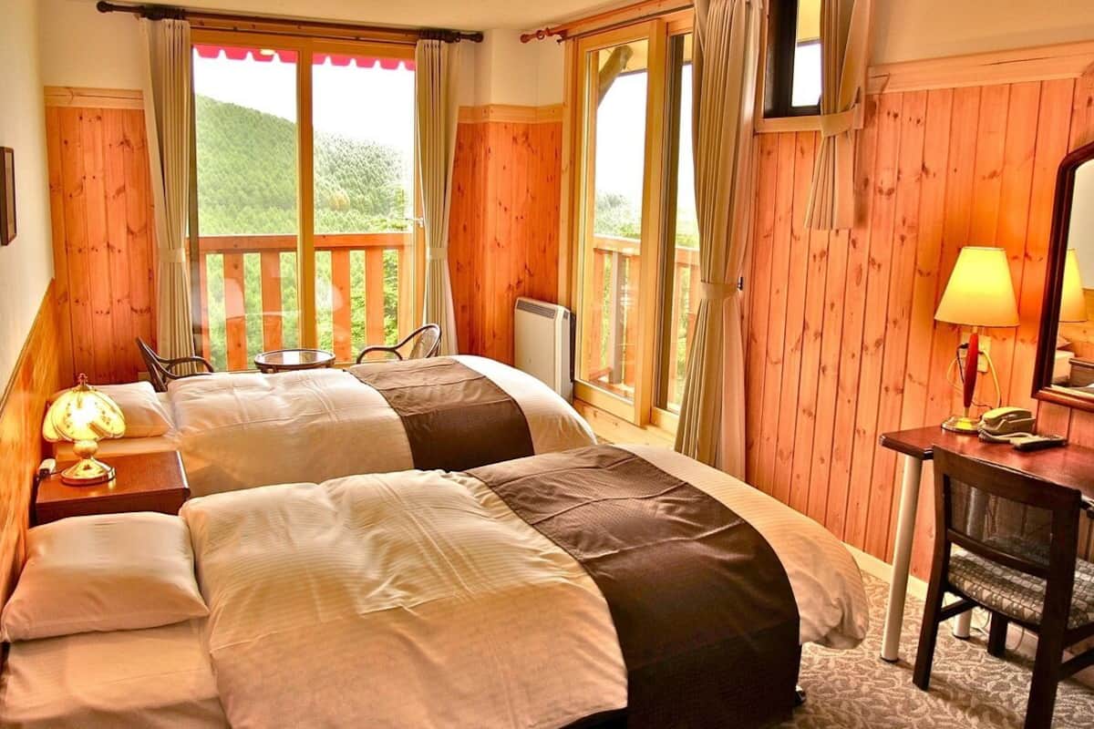 A bedroom with two beds, a desk, and a chair.