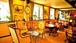 A hotel lobby with a warm color scheme, featuring a large clock, comfortable seating, and a view of the outdoors through large windows. - Hotel Andermatt (Nagawa)