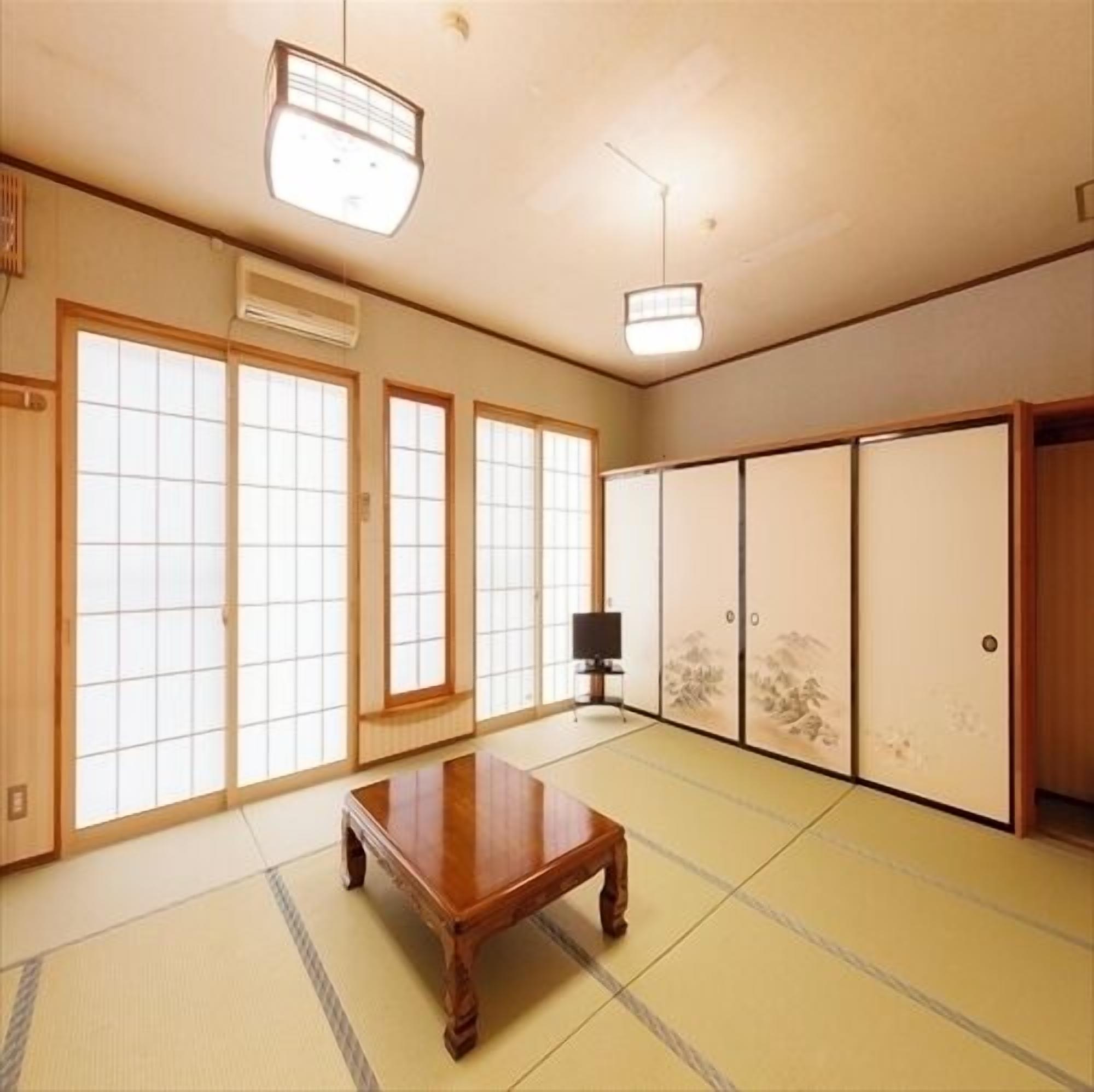 A traditional Japanese room with tatami flooring, sliding doors, and a wooden table.