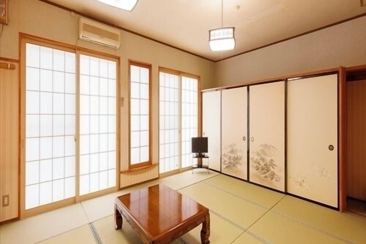 Ein traditioneller japanischer Raum mit Tatami-Böden, Schiebetüren und einem Holztisch.