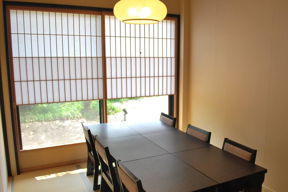 Une pièce avec une table surmontée d’un tatami, une porte coulissante de style japonais traditionnel et un luminaire suspendu.