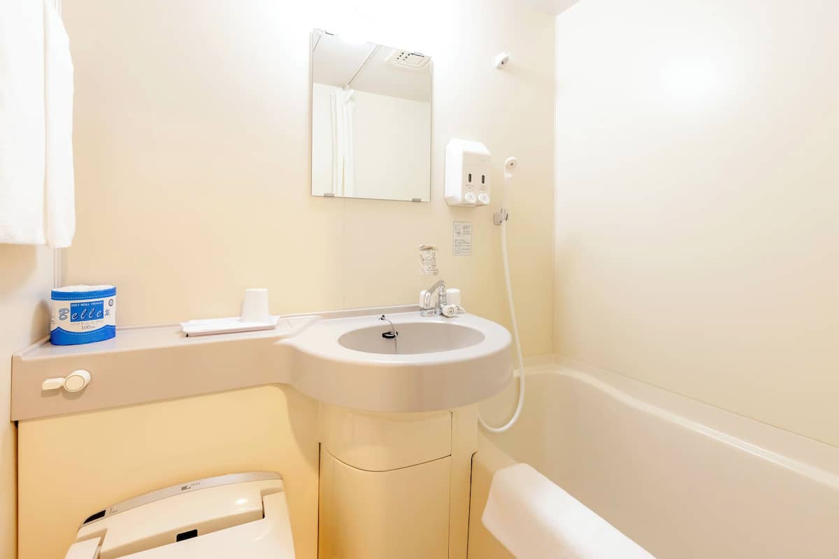 A bathroom with a sink, mirror, towel rack, and a toilet.