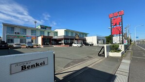 A street view with a Benkei hotel sign, a building with a signboard, and a clear blue sky. - Pension Benkei (Hachinohe)
